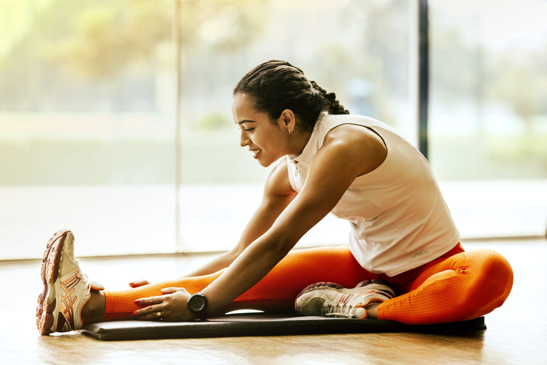 Woman sitting on a gym mat and stretching