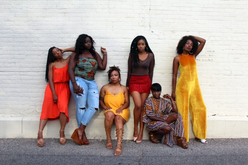 Six confident black women with bold, stylish clothes posing together