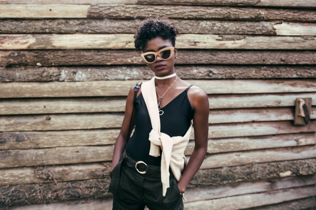 A confident black woman wearing sunglasses, posing for the camera