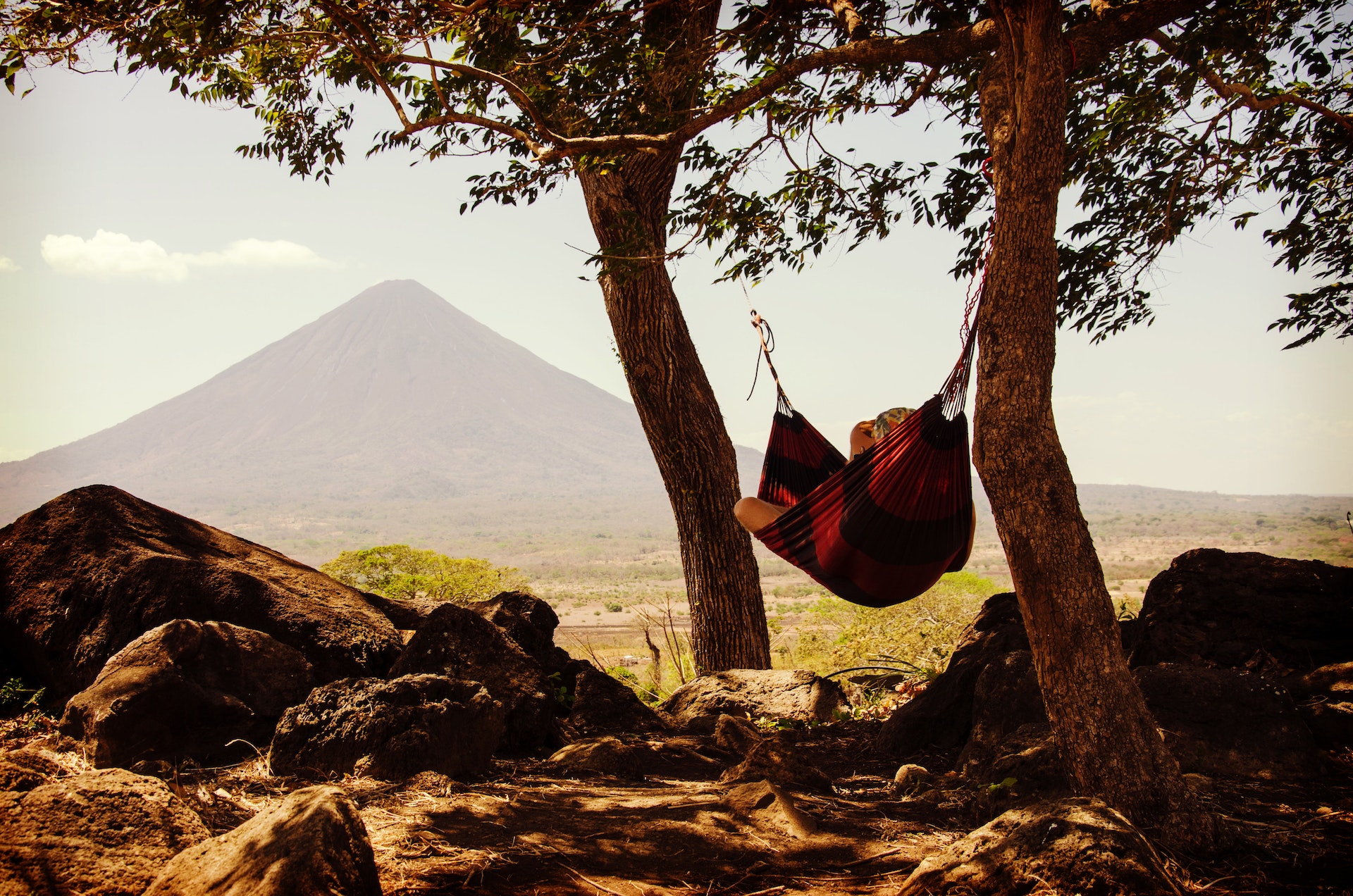 A hammock hanging between two trees with a mountain landscape in the background
