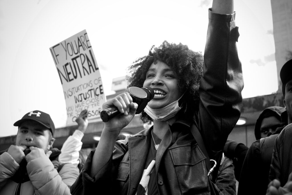 A young black woman speaking into a microphone at a protest