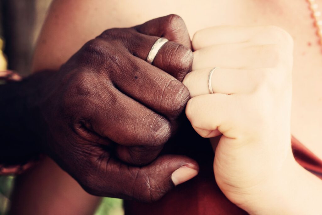 Two hands with wedding bands; one black person and one white person